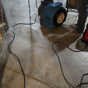 Industrial air mover drying contaminated flooring during sewage cleanup and water damage restoration