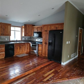 Water-damaged hardwood flooring and kitchen area affected by a broken refrigerator supply line in Medford, MN
