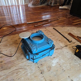 Injectidry floor drying system removing moisture from saturated subfloor during water damage restoration